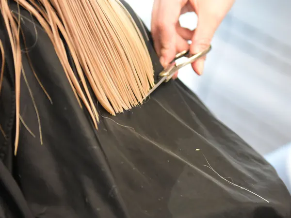 Corte de puntas sobre cabello rubio en el salón